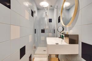 a bathroom with a white sink and a mirror at Hôtel Cocoon in Saint-Ouen
