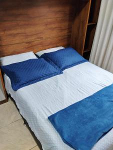 a bed with blue and white sheets and pillows at Loft Aconchegante no Centro de Niterói com AR-CONDICIONADO! in Niterói