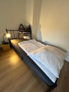 a bedroom with a bed with white sheets and a lamp at Stadtflair am Portikus in Lichtenstein-Callnberg