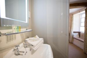 Un baño blanco con lavabo y espejo. en The Angel at Burford, en Burford
