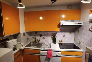 une cuisine avec des armoires orange et un évier dans l'établissement MyHome - Génépis 35 - Duplex 6 pax skis aux pieds - Val Claret, à Tignes 10 autres photos