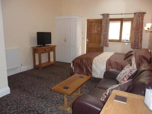 a hotel room with a couch and a bed and a tv at Old Oak Tree in Thirsk