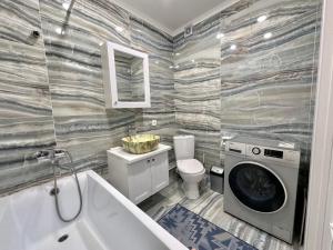 a bathroom with a washing machine and a toilet at Premium Residence, steps to center Arbat, drinking water as a gift in Almaty +8 photos