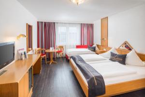 a hotel room with two beds and a flat screen tv at 4-Länder-Hotel Deutschmann in Bregenz