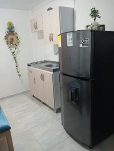 a kitchen with a black refrigerator and a stove at Apartamento cerca a Medellín - Puerta del norte Bello in Machado +23 photos