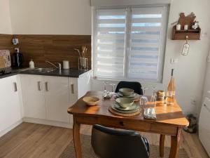 a kitchen with a wooden table with chairs and a sink at Appartement au gré des bulles in Cucq +12 photos