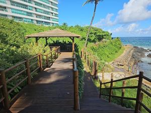 ein Holzsteg, der zu einem Strand mit einem Pavillon führt in der Unterkunft Ap70 m2 condomínio luxo Costa Espanha- Salvador- pré Carnaval -Réveillon em praia exclusiva- Vista Mar in Salvador