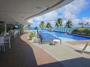 ein Resort mit Pool und Tischen und Stühlen in der Unterkunft Ap70 m2 condomínio luxo Costa Espanha- Salvador- pré Carnaval -Réveillon em praia exclusiva- Vista Mar in Salvador