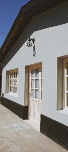 a white building with a light and a door at La Casita del Molino in Trevelin