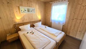 two beds in a room with wooden walls and a window at Natur Apartments Natalia in Fürth
