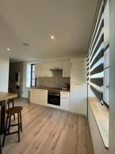 a kitchen with white cabinets and a wooden table at Le petit Château de Sathonat - Horizon Paradis in Saint-Amour-Bellevue