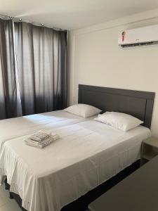 a bedroom with a large white bed with towels on it at Apt Tranquilo na Praia do Forte in Praia do Forte