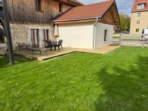 a backyard with a bench and a table and a house at La Petite Marguerite in Les Fourgs
