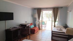 圣安尼Grand studio 4 pers superbe vue mer et cocotiers dans Village Vacances Sainte-Anne plage à - 30 m的带沙发、书桌和电视的客厅