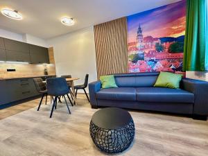 Una sala de estar con un sofá azul y una cocina. en Luxusní Apartmány Krumlovský Vltavín, en Český Krumlov