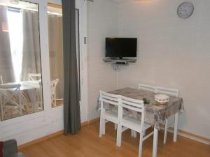 une salle à manger avec une table, des chaises et une télévision dans l'établissement Coquet studio à Le Dévoluy de 24 m², à Saint-Étienne-en-Dévoluy