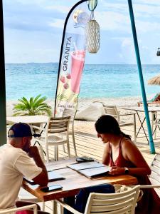 a man and woman sitting at a table on the beach at Luna Mare Boutique Seaside in Borsh