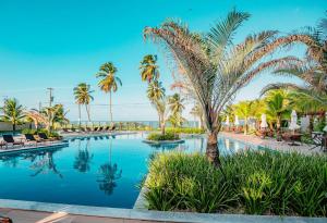 a swimming pool with palm trees and the ocean at Blue Beach Resort Residence Cabedelo-João Pessoa PB AP 2 quartos - 70 m2 in Cabedelo