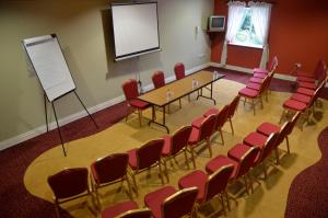a conference room with a table and red chairs at Cooneys Hotel in Ballymahon