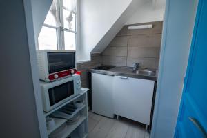 une petite cuisine avec un évier et un micro-ondes dans l'établissement LA PERLE APPART - PLEIN CENTRE VILLE Orléans, à Orléans