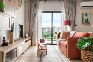 a living room with a couch and a tv at Title Halo Orange Sunset 46m2 Naiyang Pool&Gym in Nai Yang Beach