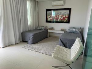 a bedroom with two beds and a tv on the wall at Loft excelente no centro de Governador Valadares in Governador Valadares
