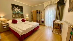 a bedroom with a large bed with red pillows at Casteluce Hotel Funivie in Pinzolo