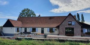 a house with a tiled roof on a field at Au chemin du paradis Gîte de 10 personnes 4 Etoiles in Saint-Martin-lez-Tatinghem