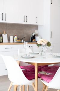 a white kitchen with a white table and chairs at ATENEO - Studio DeLuxe MODERN Apartment, BIG Balcony, Plus FREE Parking in Timişoara