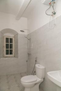 a white bathroom with a toilet and a sink at Zanzibar Vintage House in Stone Town +68 photos