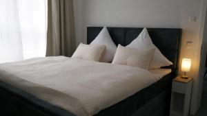a bed with white sheets and pillows next to a window at Exclusives, urbanes 3-Zimmer Appartement in Nürnberg