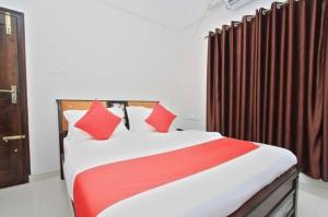 a bedroom with a large bed with red pillows at Royal Guest inn HSR Layout in Bangalore