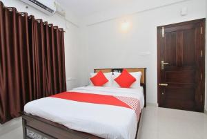 a bedroom with a large bed with red pillows at Royal Guest inn HSR Layout in Bangalore
