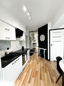 a kitchen with white cabinets and a wooden floor at Apartament Niko in Gniezno
