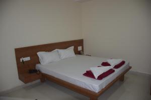 a bed with white sheets and red towels on it at Shrinivas Lodge in Dhārwād