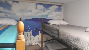 una camera da letto con un letto e un dipinto sul muro di The Rabbit Hole Hostel Fira a Firà
