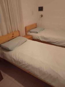 2 Betten in einem kleinen Zimmer mit weißer Bettwäsche in der Unterkunft Casa Entera in Cordoba