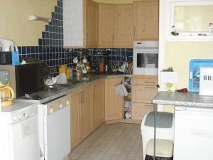 una cucina con armadietti in legno ed elettrodomestici bianchi di The Old Coach House a Belle-Isle-en-Terre