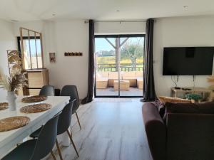 a living room with two tables and a flat screen tv at Le petit Château de Sathonat - Horizon Paradis in Saint-Amour-Bellevue