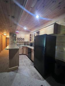 een keuken met een zwarte koelkast in een kamer bij Welcome to Bear's Den Lodge in Round Lake Seaplane Base