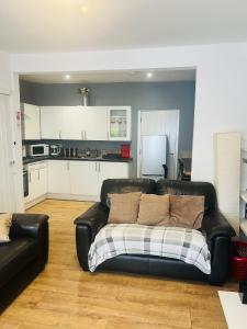 a black leather couch sitting in a living room at Jrs place in Merthyr Tydfil +7 photos