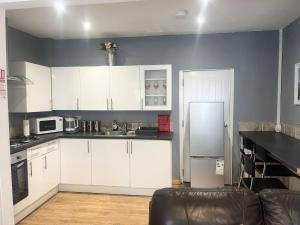a kitchen with white cabinets and a refrigerator at Jrs place in Merthyr Tydfil