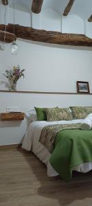 a bedroom with a bed with a green comforter at Apartamentos Casa de los Galeote in Baeza