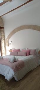 a large bed with pink and white pillows on it at Apartamentos Casa de los Galeote in Baeza