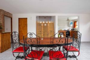 a dining room table with red chairs in a kitchen at Casa, Bosque y Mar in Miramar
