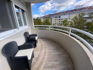 a balcony with two chairs and a railing with a view at Svetao stan sa terasom blizu Ade - Casa 29 in Čukarica