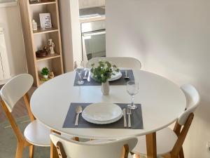 a white dining room table with white plates and silverware at Svetao stan sa terasom blizu Ade - Casa 29 in Čukarica +22 photos
