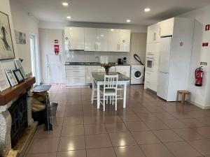 a kitchen with white cabinets and a table and chairs at Casa de Casarelhos - "Gerês" - Estúdio piso 0 - Apartamento Piso 1 in Geres
