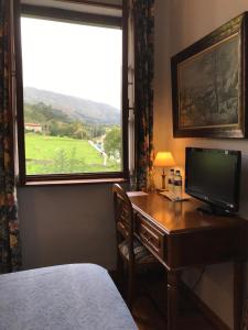a bedroom with a desk with a television and a window at Hotel Rural Villa Elena in Panes