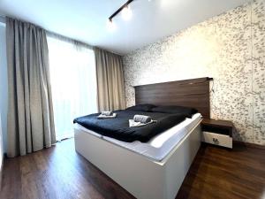 a bedroom with a large bed and a large window at Apartmán Manhattan s terasou v centre mesta in Trenčín